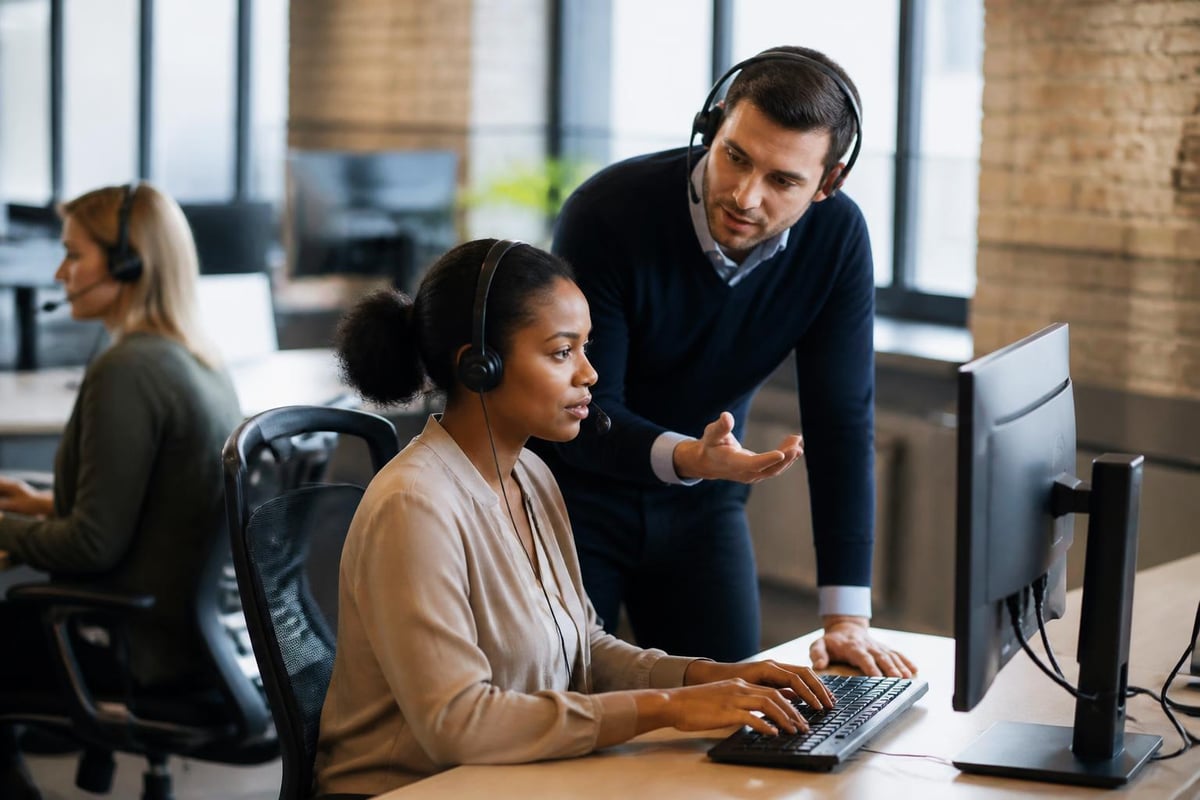 Employee receiving coaching in a contact center, engaged in real-time quality management, with a supervisor providing feedback and guidance during a live interaction.